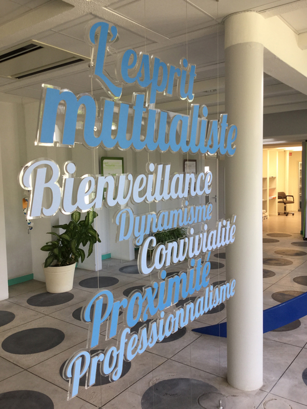 Lettre en plexi suspendues par des filins dans l'espace d'accueil